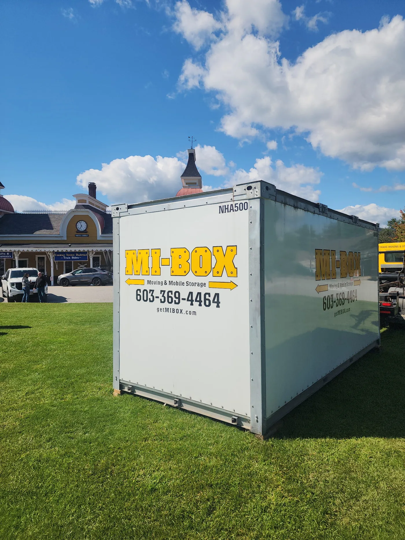 MI-BOX portable storage container on the lawn at Schouler Park in North Conway for Bark in the Park, with the historic railroad depot behind it